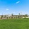 a grassy field with a fence and trees in the background