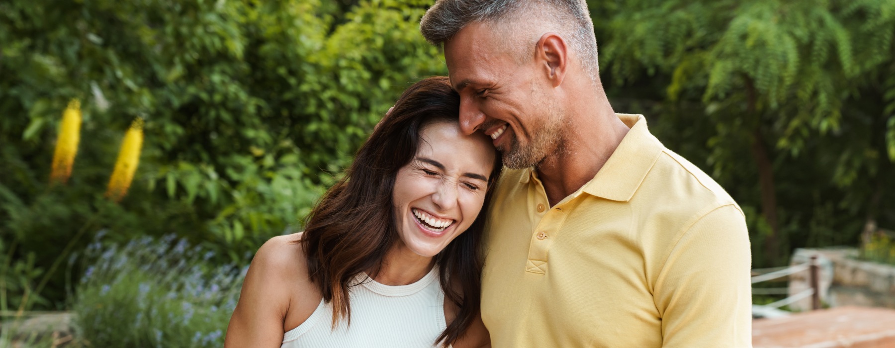 A couple laughing and embracing outdoors near River Rock at Blume Road Apartments in Mooresville, NC.