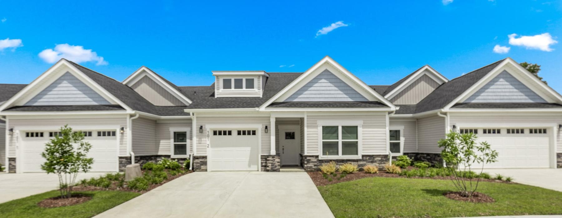 a row of houses with paved driveways and a blue sky in the background