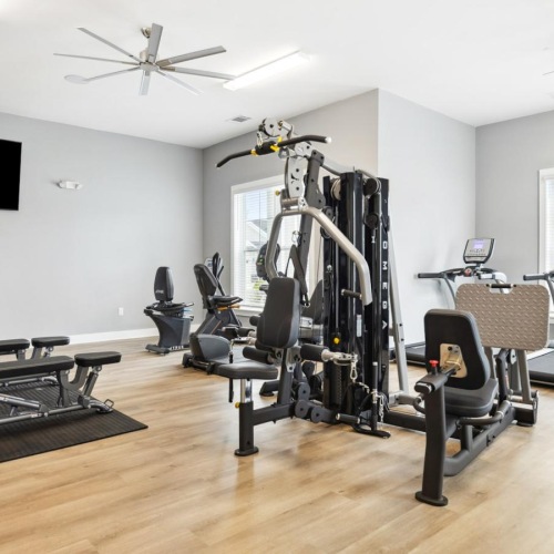 Get your workout on The fitness center at River Rock at Blume Road homes for rent in Mooresville, NC, featuring wood grain floor paneling.